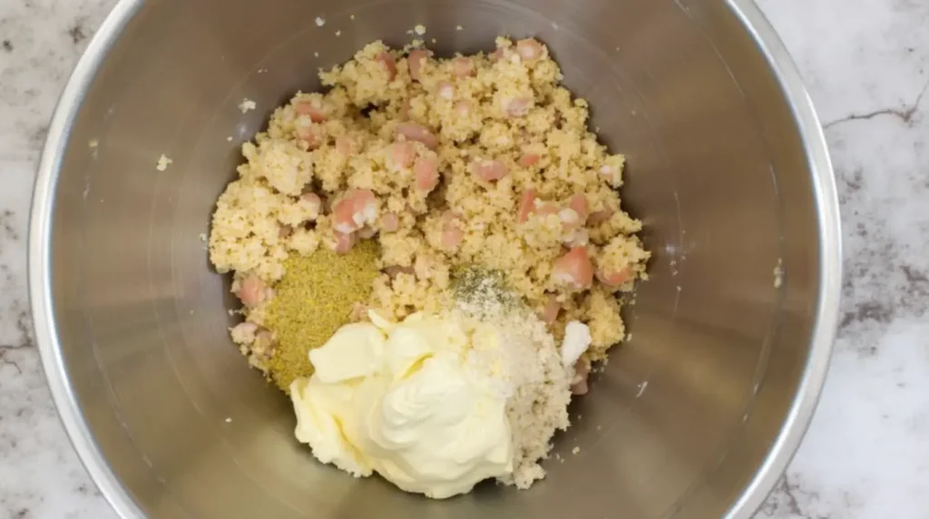 A bowl with crabmeat, breadcrumbs, mayonnaise, and seasonings being mixed together to make the stuffing.